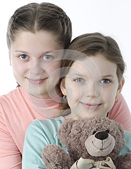 Portrait of pretty little girls holding teddy bear on white