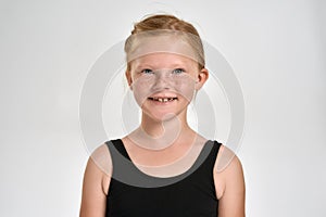 Portrait of pretty little red haired sportive girl in sportswear smiling at camera while standing isolated over white