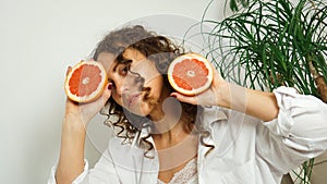 Portrait of pretty middle-aged woman with curly hair with grapefruit