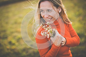 Portrait of a pretty middle-aged  woman outside in a park, picking flowers