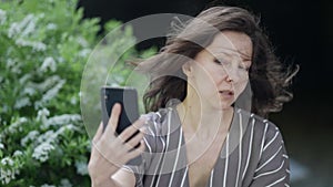 portrait of pretty middle-aged woman taking selfie by smartphone outdoors