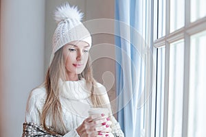 Portrait of pretty model woman brunette wearing season casual clothes white sweater and knitted hat holding hot dreank