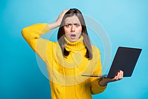 Portrait of pretty outraged girl holding in hands laptop bad news finance fail isolated over bright blue color