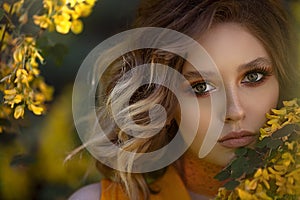 Portrait of a Pretty sensual woman on a background of a yellow blossom tree. Summer time, summer colors.