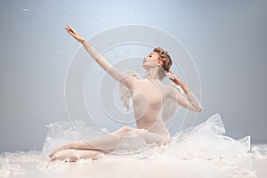 Portrait of pretty, slim beautiful young girl, graceful ballerina in image of angel with wings sitting on cloud isolated