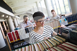 Portrait of a pretty smiling girl reading book in library