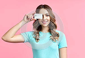 Portrait of a pretty smiling woman holding credit card at her face