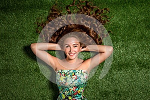 Portrait of pretty smiling young woman, laying on the grass