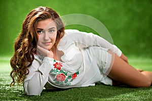 Portrait of pretty smiling young woman, laying on the grass