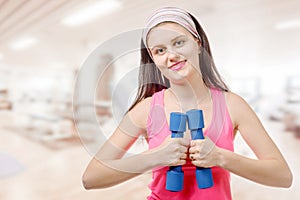 Portrait of pretty sporty girl holding weights