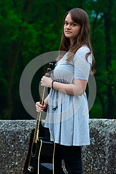 Portrait of pretty teen girl holding guitar