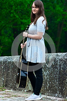 Portrait of pretty teen girl holding guitar
