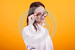 Portrait of pretty teenage girl with eyeglases in studio over yellow background