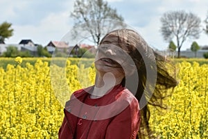 Girl in canola field with wild flying hair