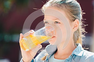 Portrait of a pretty teenage girl holding glass with tasty orange juice