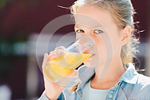 Portrait of a pretty teenage girl holding glass with tasty orange juice