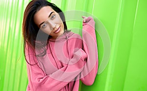 Portrait of pretty teenage girl smiling and looking directly to the camera, wearing pink hoodie. Beautiful young female has dreamy