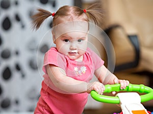 Portrait of pretty child girl standing with baby walker