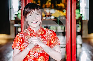 Portrait pretty woman in cheongsam qipao red dress making salute , in the Chinese New Year.