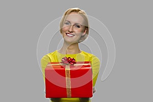 Portrait of pretty woman handing gift box to someone.