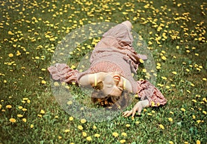 Portrait of pretty woman lying down on dandelions field with closed eyes in red dress. Spring. Allergy and mites in green grass.