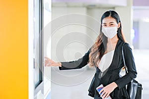 Portrait of pretty woman with mask stand in front of door of sky train on the platform during coronavirus pandemic in city