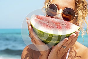 Portrait of pretty woman and red fresh watermelon with blue sea and sky in background. Concept of summer holiday vacation. Healthy