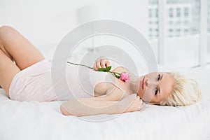 Portrait of a pretty woman resting in bed with rose