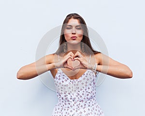 Portrait pretty woman sends air kiss and Shows the sign of the heart with your fingers on background