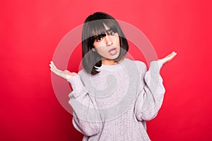 Portrait of a pretty woman shrugging shoulders isolated on a red background