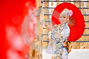 Portrait of pretty woman wear japanese style dress and hold red umbrella during attractive on wood banner in front of row of