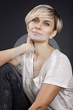 Portrait of a pretty woman wearing a white T-shirt and black jeans. Cute smiling blonde 35-40 years old. Calm and confident. Black