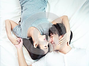 Portrait of pretty young asian couple with happiness. asia man and woman lay on bed facing together with big smile hand cover face