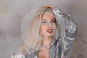 Portrait of a pretty young blonde woman with blue eyes with plump sexy lips in a fashionable gray summer shirt with a pattern
