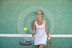 Portrait of a pretty, young, female tennis player in front of a training wall