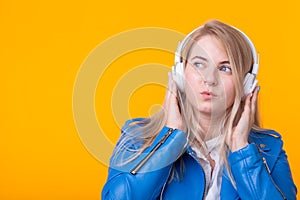 Portrait of pretty young girl blonde female student holding smartphone with blue leather jacket headphones posing on a