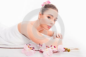 Portrait of pretty young girl lying in spa and relaxing with orchid