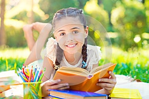 Portrait of pretty young girl reading book in park