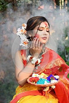 Portrait of pretty young indian girl wearing traditional saree and jewellery, holding powder colours in plate on the festival of