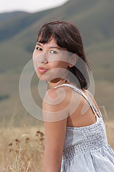 Portrait of a pretty young lady on a meadow hills