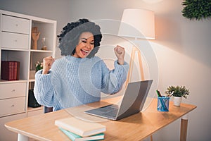 Portrait of pretty young lady wear sweater raise fists achievement laptop desk home office indoors