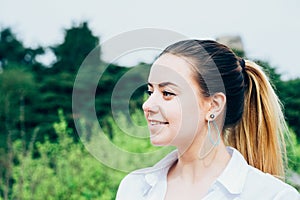 a pretty young woman in white shirt, smiling, heart shaped earing