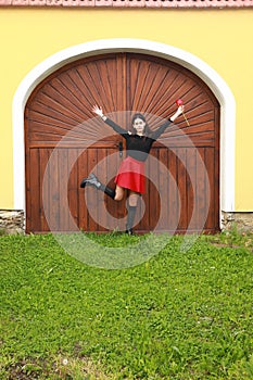 Portrait of pretty young teen girl with red tulip dancing by gate