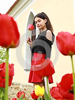 Portrait of pretty young teen girl among red tulips