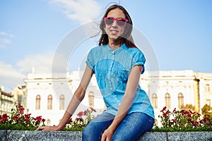 Portrait of pretty young teenage girl in pink sunglasses sitting