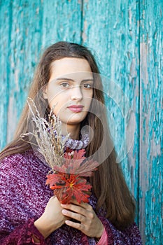Portrait of a pretty young teenage girl 13-16 years old. Young woman with autumn flowers closeup
