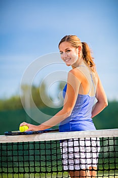 Portrait of a pretty, young tennis player on a court