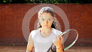 Portrait of pretty young tennis playgirl with racket smiling and going at camera photo