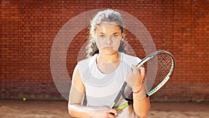 Portrait of pretty young tennis playgirl with racket smiling and going at camera photo