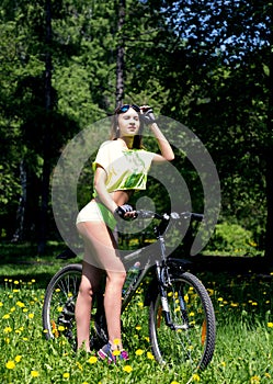 Portrait of pretty young woman with bicycle in a park - outdoor